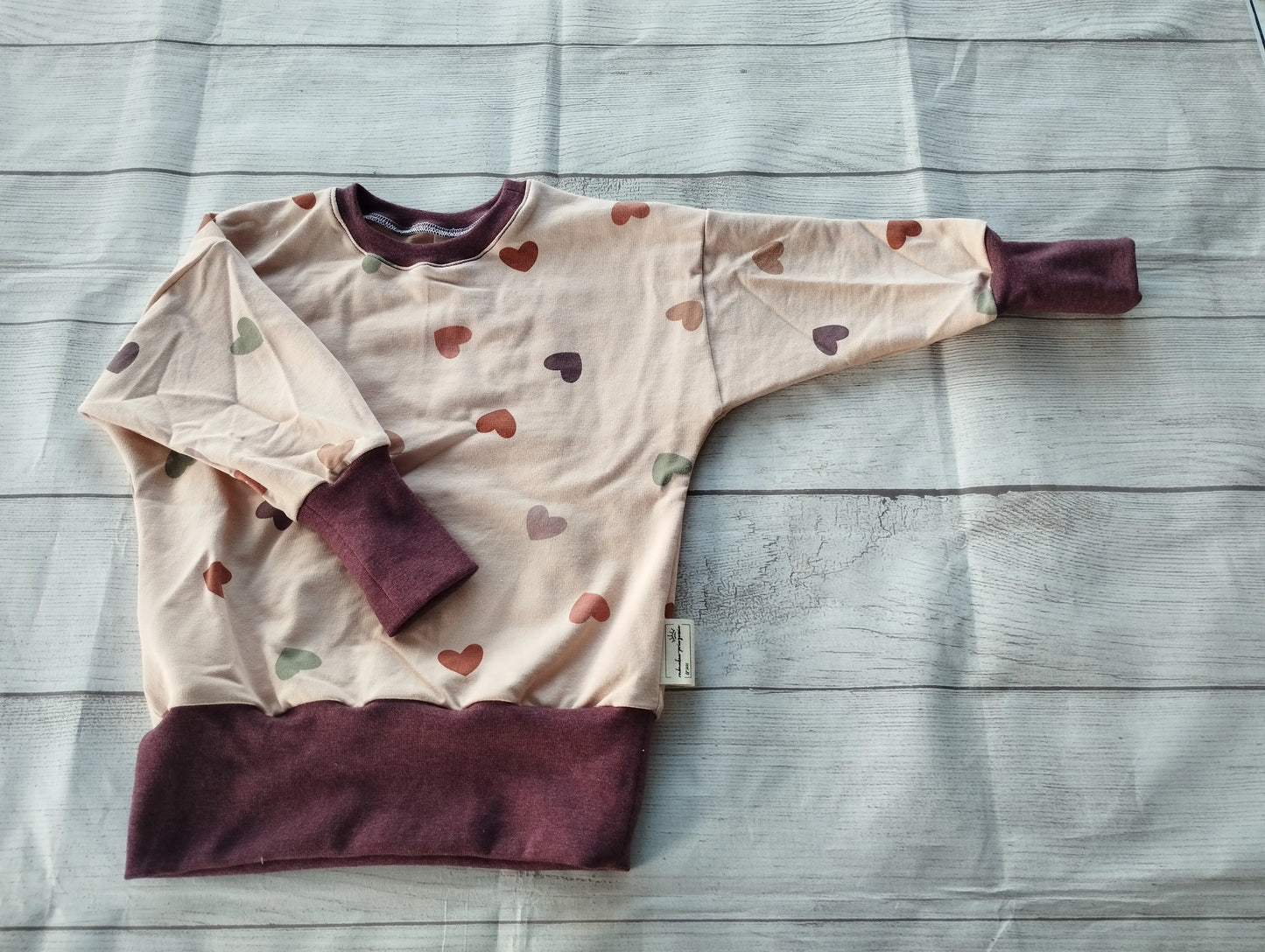 Kinderpullover mit Herzchen-Muster aus OEKO-TEX zertifiziertem French Terry, handgemacht in Oldenburg, Einzelgröße, beige mit bordeauxfarbenen Bündchen.