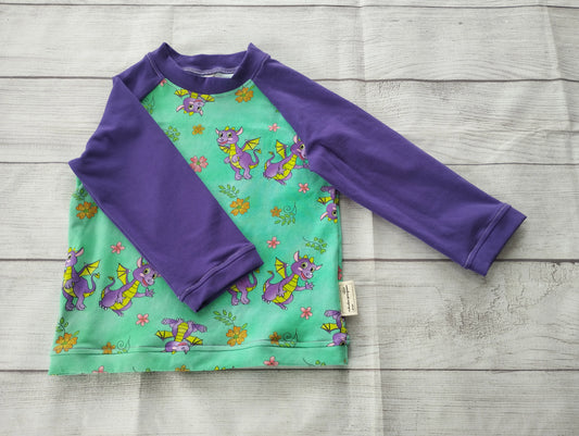 Kinder-Raglanshirt mit grünem Drachen-Muster und lila Ärmeln – handgemacht aus elastischem Baumwolljersey