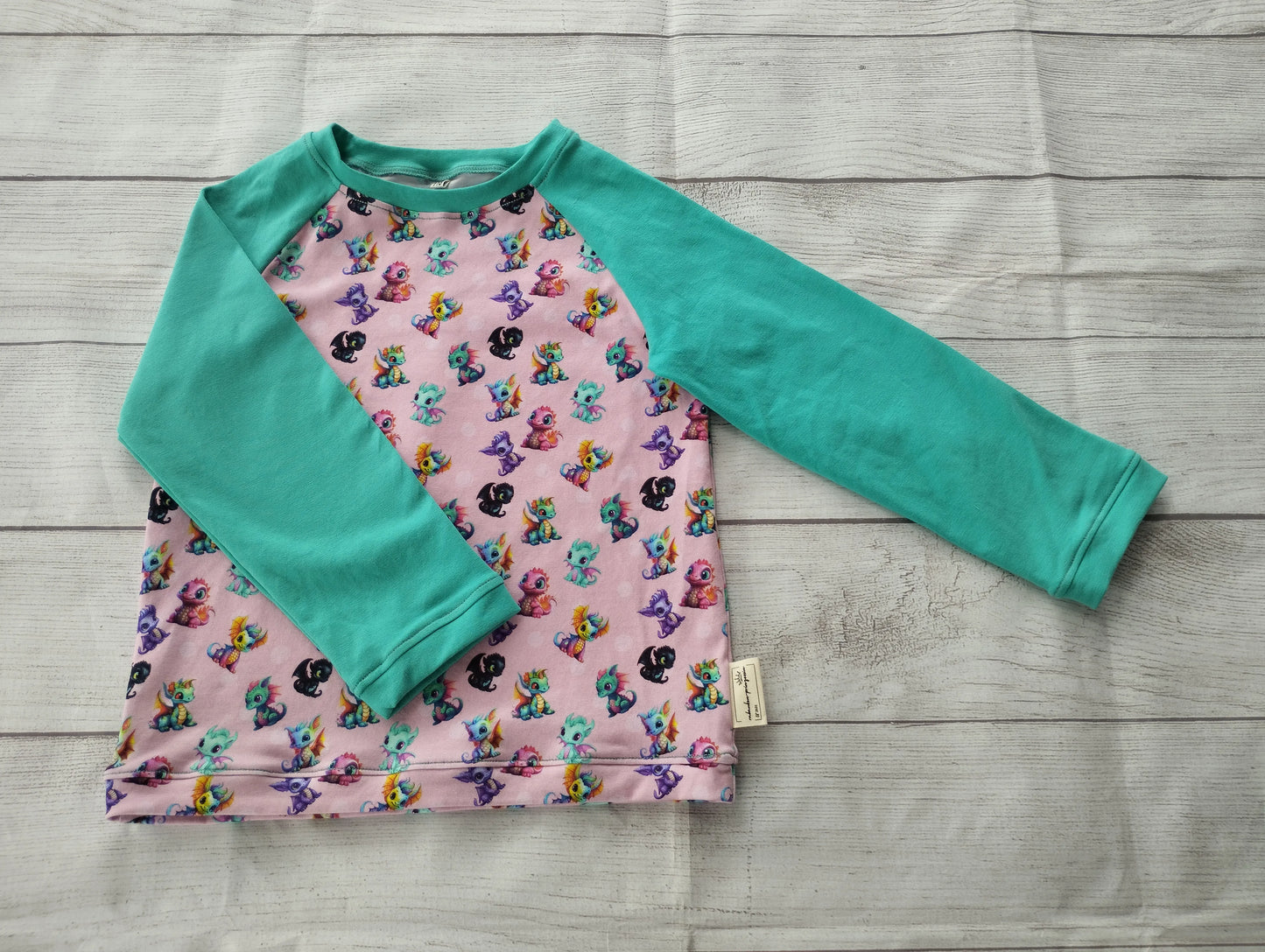 Kinder-Raglanshirt mit rosa Drachen-Muster und türkisfarbenen Ärmeln – handgemacht aus elastischem Baumwolljersey