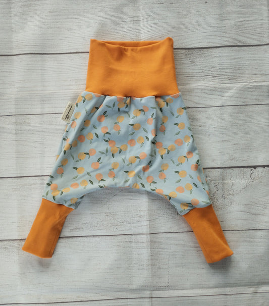 Mitwachshose für Babys mit Pfirsich-Muster auf hellblauem Stoff und orangefarbenen Bündchen – handgemacht aus elastischem Baumwolljersey