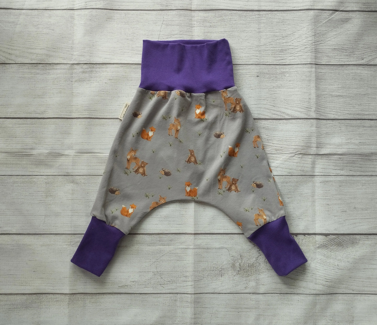 Mitwachshose für Babys mit Waldtier-Muster auf grauem Stoff und lila Bündchen – handgemacht aus elastischem Baumwolljersey