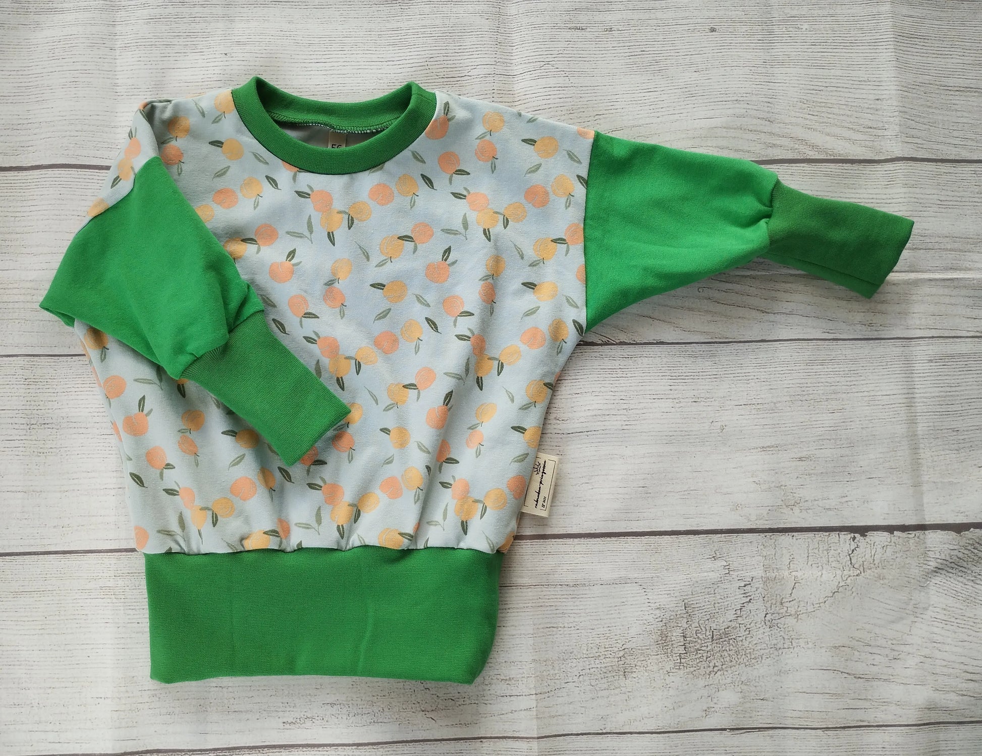 Kinderpullover mit Pfirsichmuster und grünen Bündchen – handgemacht aus elastischem Baumwolljersey