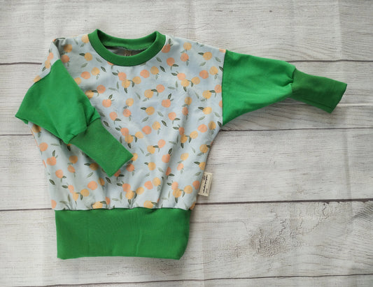 Kinderpullover mit Pfirsichmuster und grünen Bündchen – handgemacht aus elastischem Baumwolljersey