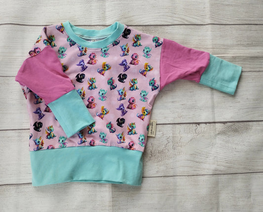 Langarmshirt für Babys mit lila Vorderteil und buntem Fantasie-Muster – pinker und türkisfarbener Ärmel, handgemacht aus Baumwolljersey mit Einhorn- und Tiermotiven