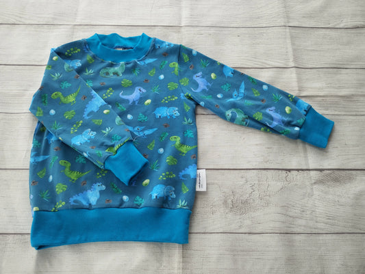 Kinderpullover mit grün-blauem Dino-Muster und blauen Bündchen – handgemacht aus elastischem Baumwolljersey