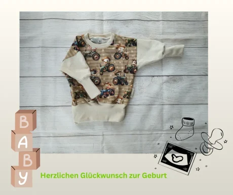 Baby-Pullover mit Traktor-Motiv auf Holzuntergrund, daneben Holzklötze mit "Baby" und gezeichnete Symbole zur Geburt